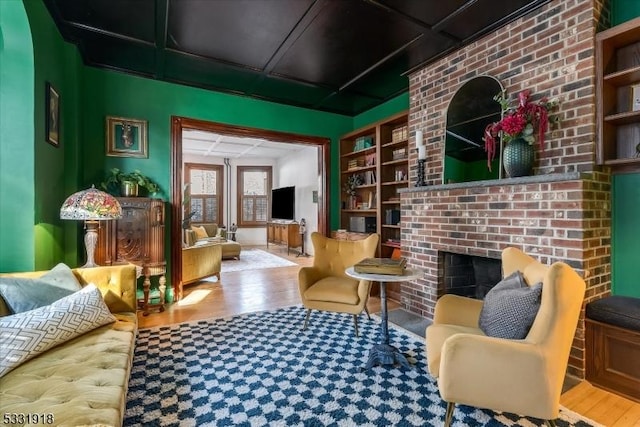 living room featuring hardwood / wood-style flooring, built in shelves, and a fireplace