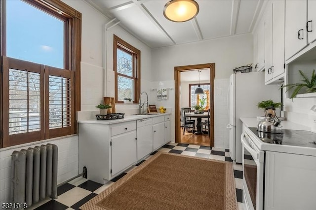 kitchen featuring sink, white cabinetry, white appliances, and radiator heating unit