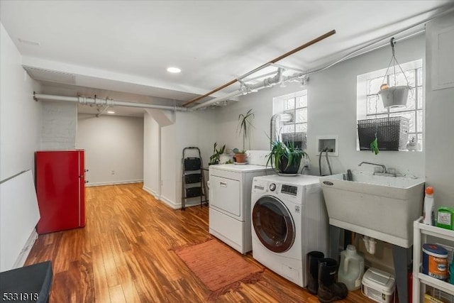 clothes washing area with sink, light hardwood / wood-style flooring, and separate washer and dryer