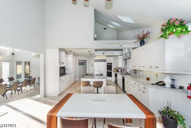 kitchen with white cabinetry, a center island, double wall oven, and black dishwasher