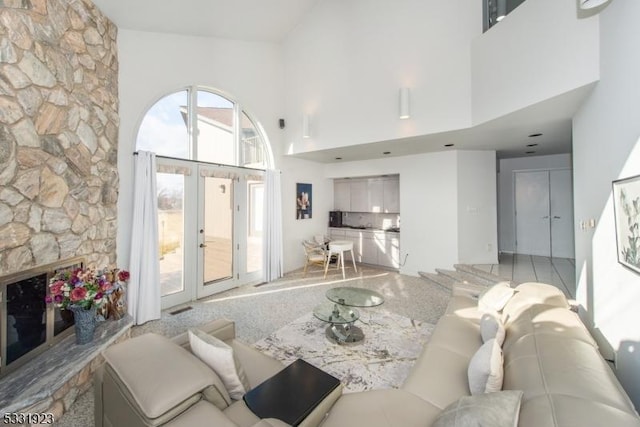 living room featuring a fireplace, a healthy amount of sunlight, and a high ceiling