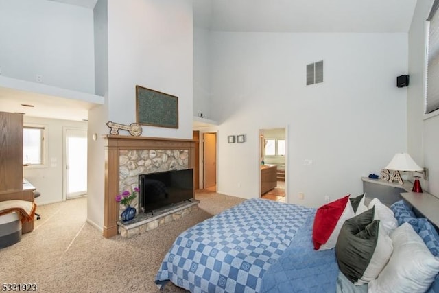 carpeted bedroom with high vaulted ceiling and a stone fireplace