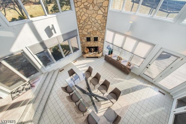 living room with tile patterned flooring, a stone fireplace, and plenty of natural light