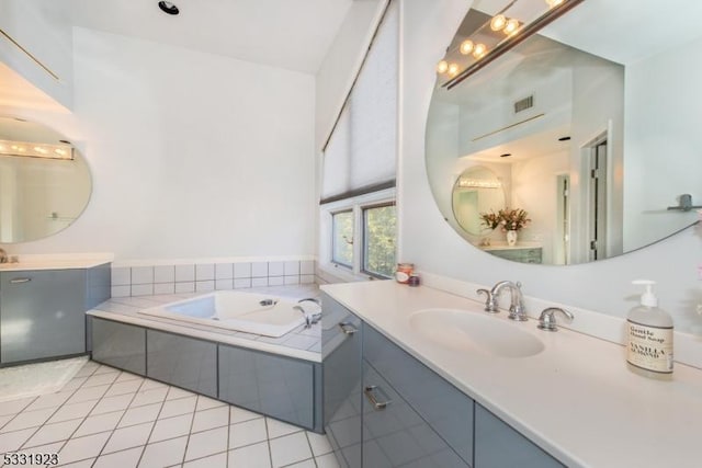 bathroom featuring tile patterned flooring, vanity, and a relaxing tiled tub