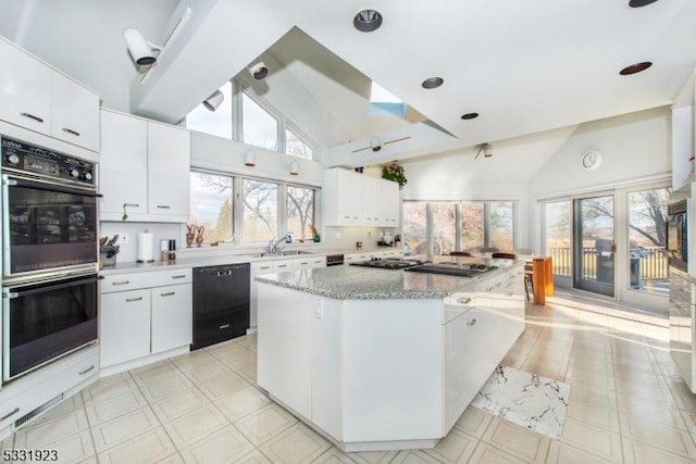 kitchen featuring light stone countertops, sink, black appliances, white cabinets, and a kitchen island