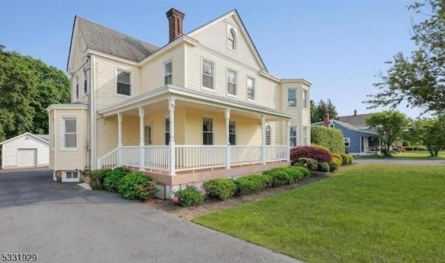 view of front of property with an outbuilding, a porch, a garage, and a front lawn