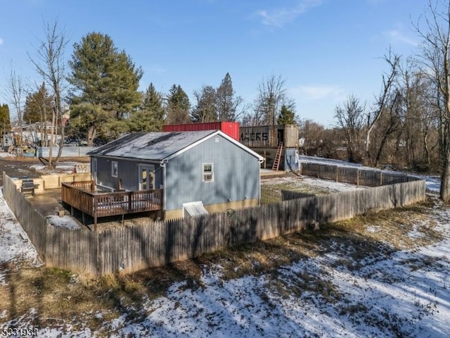 snow covered back of property featuring a wooden deck