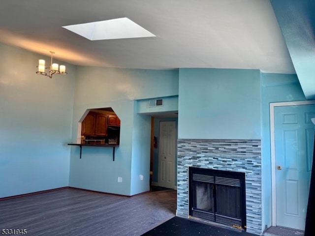 kitchen featuring hanging light fixtures, a notable chandelier, lofted ceiling with skylight, refrigerator, and a fireplace