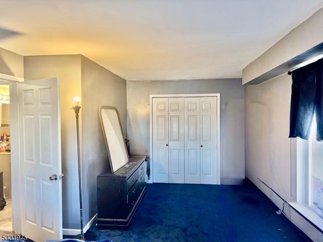 unfurnished bedroom with dark colored carpet and a closet