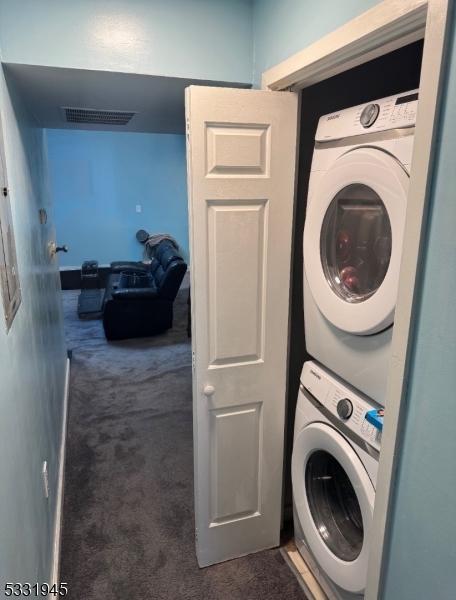 washroom with dark colored carpet and stacked washing maching and dryer