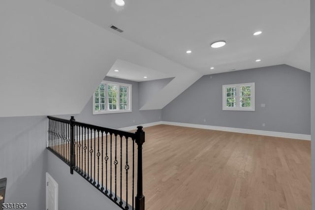 additional living space with vaulted ceiling and light hardwood / wood-style flooring