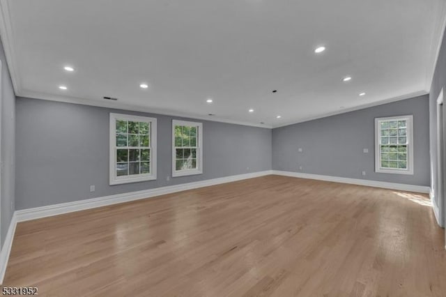 spare room featuring a healthy amount of sunlight, light wood-type flooring, and ornamental molding