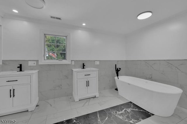 bathroom with a washtub, vanity, tile walls, and ornamental molding