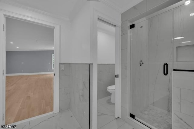 bathroom with crown molding, a shower with shower door, tile walls, and toilet