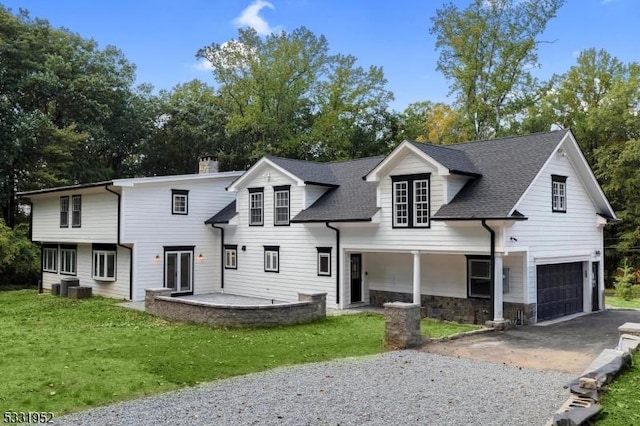 view of front of house with cooling unit, a garage, and a front yard