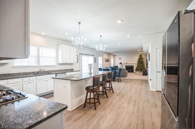 kitchen with appliances with stainless steel finishes, light wood-type flooring, a breakfast bar, a kitchen island, and white cabinets