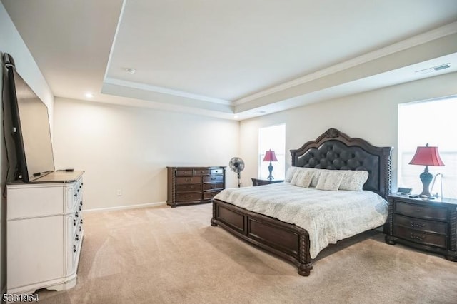 carpeted bedroom featuring ornamental molding and a tray ceiling