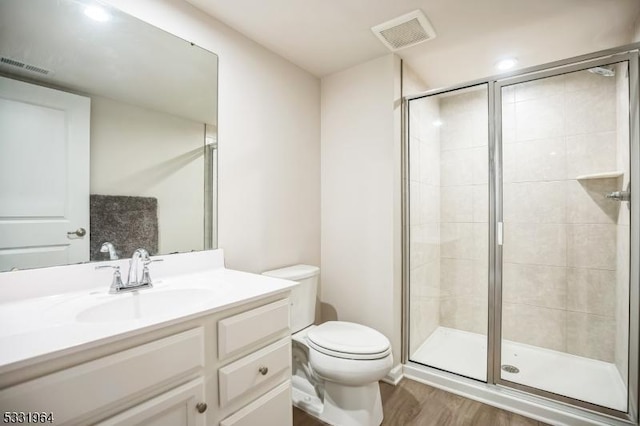 bathroom featuring toilet, wood-type flooring, vanity, and a shower with shower door