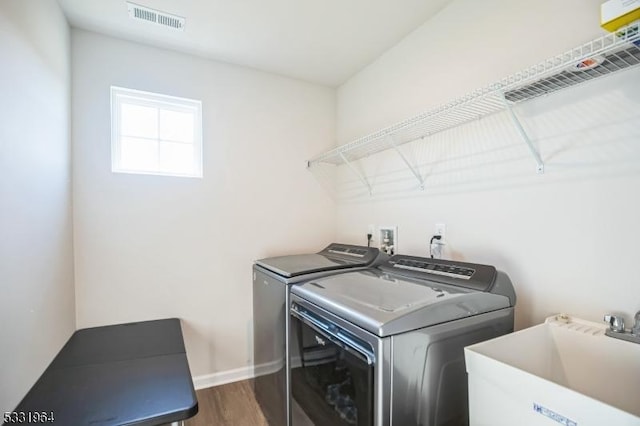 laundry area featuring dark hardwood / wood-style floors, washer and clothes dryer, and sink