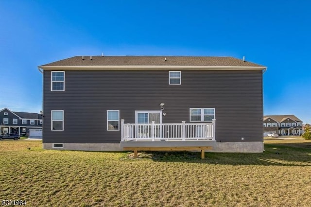 rear view of property featuring a wooden deck and a lawn