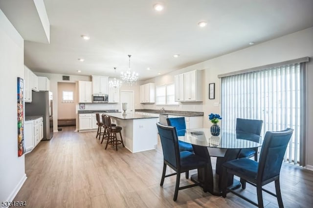 dining space with a notable chandelier and light wood-type flooring