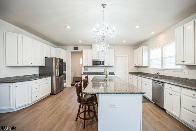 kitchen featuring decorative light fixtures, a center island, white cabinetry, and appliances with stainless steel finishes