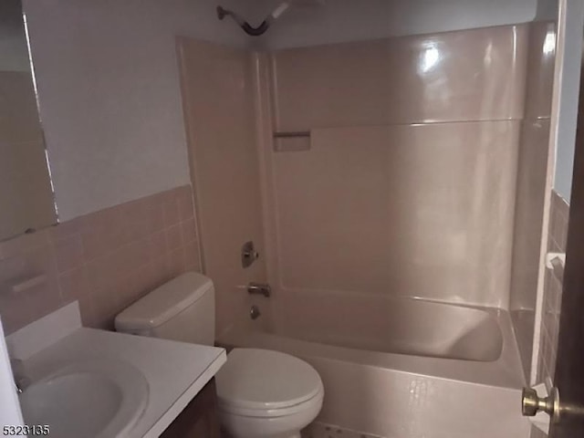 full bathroom featuring shower / bathing tub combination, vanity, toilet, and tile walls