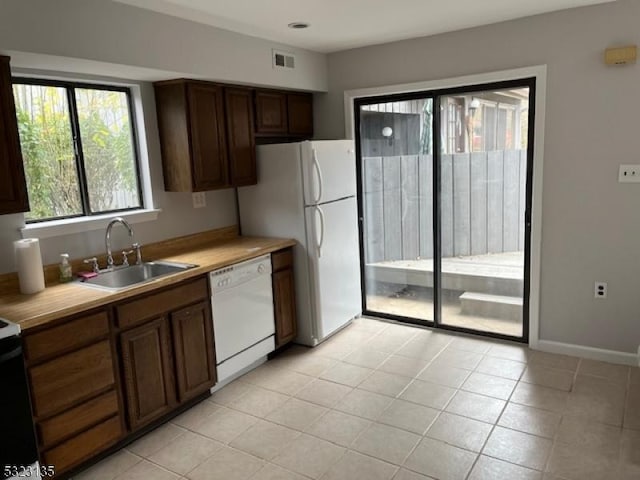 kitchen featuring white appliances, sink, and light tile patterned floors