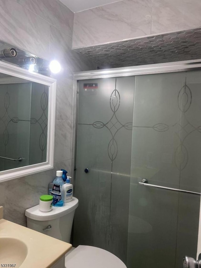 bathroom with vanity, toilet, and tile walls