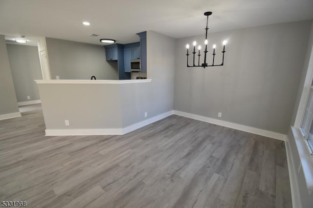 unfurnished dining area with hardwood / wood-style floors and an inviting chandelier