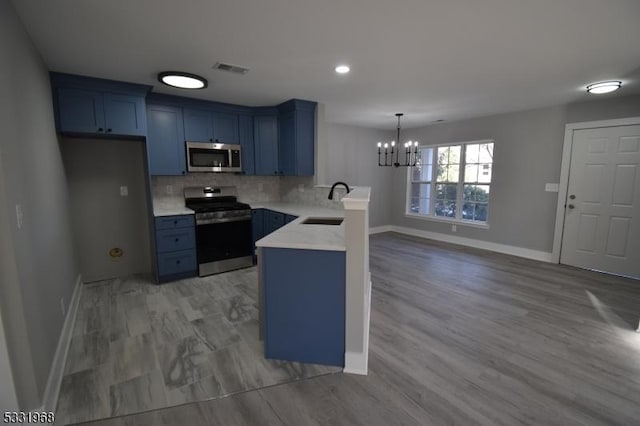 kitchen with a notable chandelier, blue cabinets, sink, and appliances with stainless steel finishes