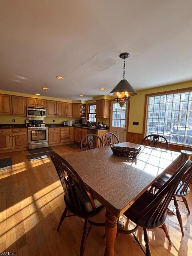 dining area with an inviting chandelier, light hardwood / wood-style floors, and wooden walls