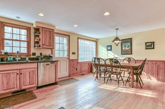 kitchen with sink, stainless steel dishwasher, light hardwood / wood-style floors, and decorative light fixtures