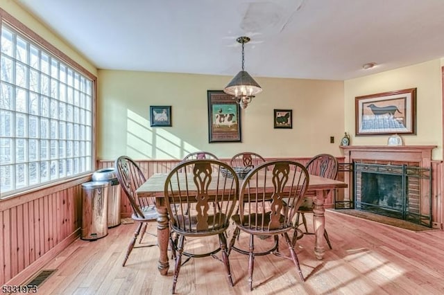 dining space featuring light hardwood / wood-style floors, wooden walls, and a notable chandelier