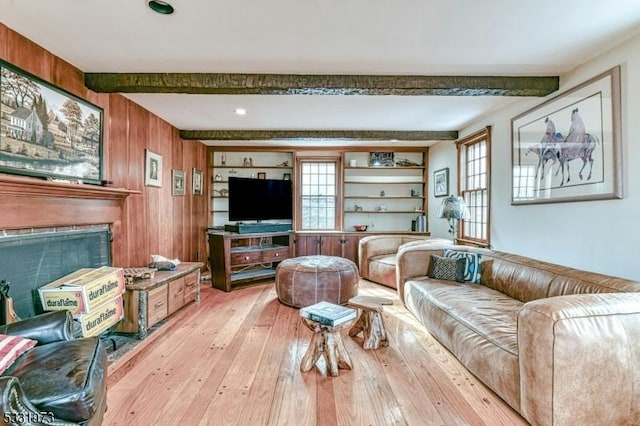 living room with light hardwood / wood-style floors, a fireplace, beamed ceiling, and wooden walls