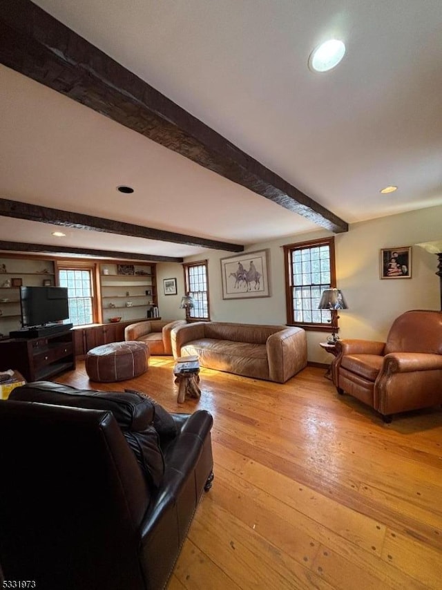 living room featuring plenty of natural light, light hardwood / wood-style flooring, and beamed ceiling