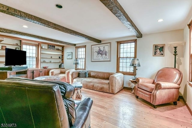 living room with a wealth of natural light, beam ceiling, light hardwood / wood-style flooring, and built in shelves