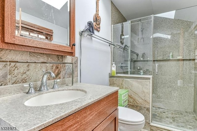 bathroom with vanity, toilet, tasteful backsplash, and walk in shower