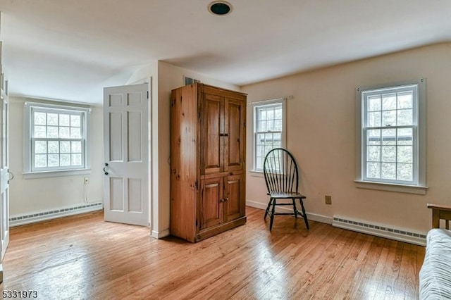 interior space with a baseboard heating unit and light hardwood / wood-style flooring