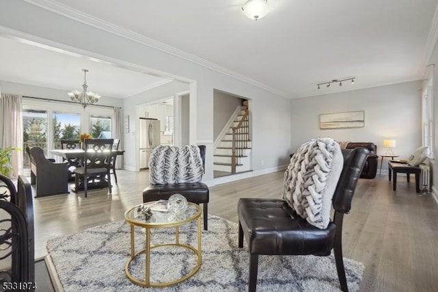 living room with hardwood / wood-style flooring, ornamental molding, and an inviting chandelier