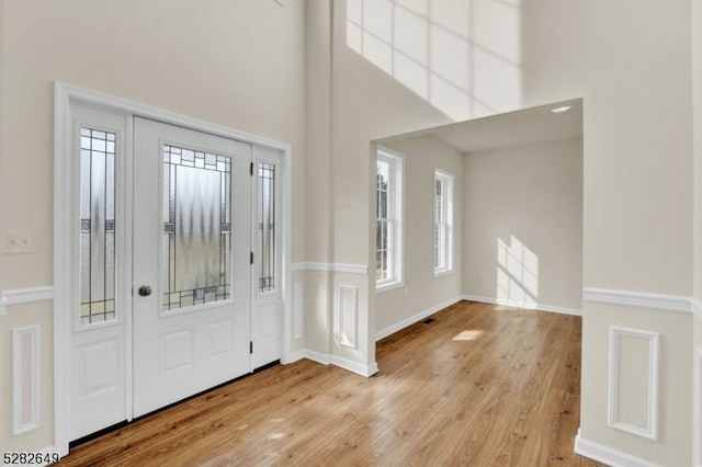 entryway with a towering ceiling and light hardwood / wood-style flooring