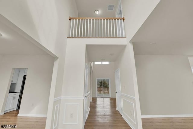 hallway with a towering ceiling and light hardwood / wood-style floors