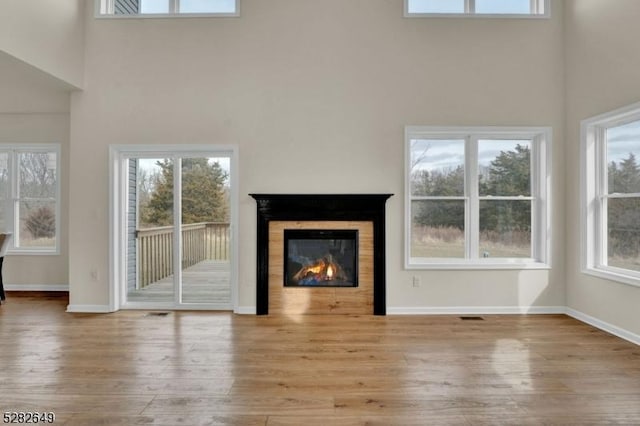 unfurnished living room featuring light hardwood / wood-style floors and a high ceiling