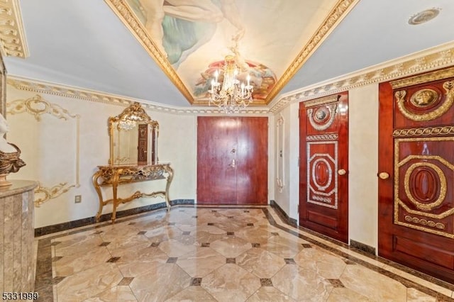 entryway featuring a raised ceiling, an inviting chandelier, and crown molding