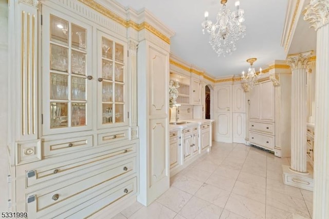 bathroom with vanity, an inviting chandelier, ornamental molding, and ornate columns