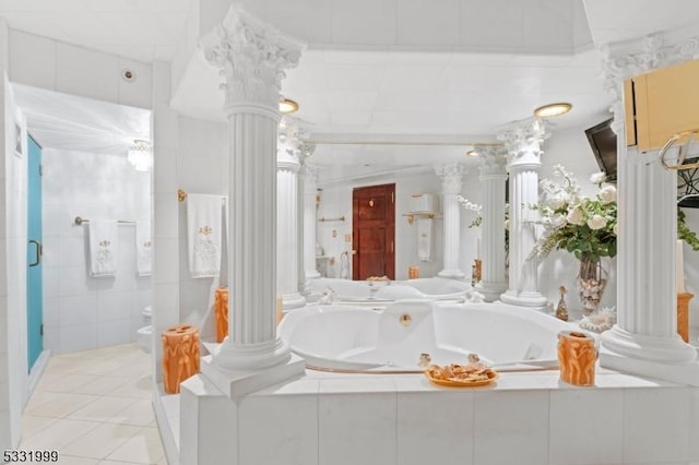 bathroom featuring tile patterned floors, ornate columns, and tiled tub