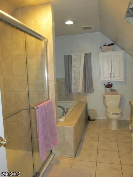 bathroom with tile patterned flooring, independent shower and bath, and toilet