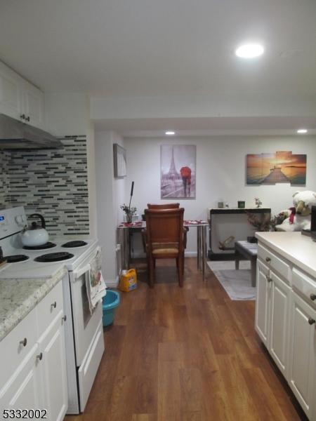 kitchen featuring white cabinets, decorative backsplash, dark hardwood / wood-style flooring, and white electric stove