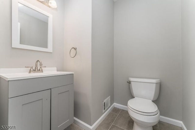 bathroom with toilet, vanity, and tile patterned flooring