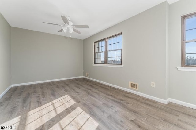 empty room with ceiling fan, plenty of natural light, and light hardwood / wood-style floors